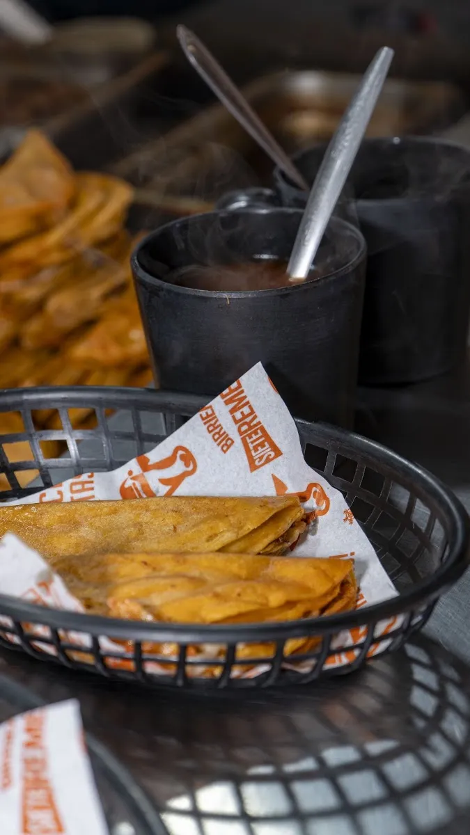 Tacos dorados de birria en una canasta, con consomé