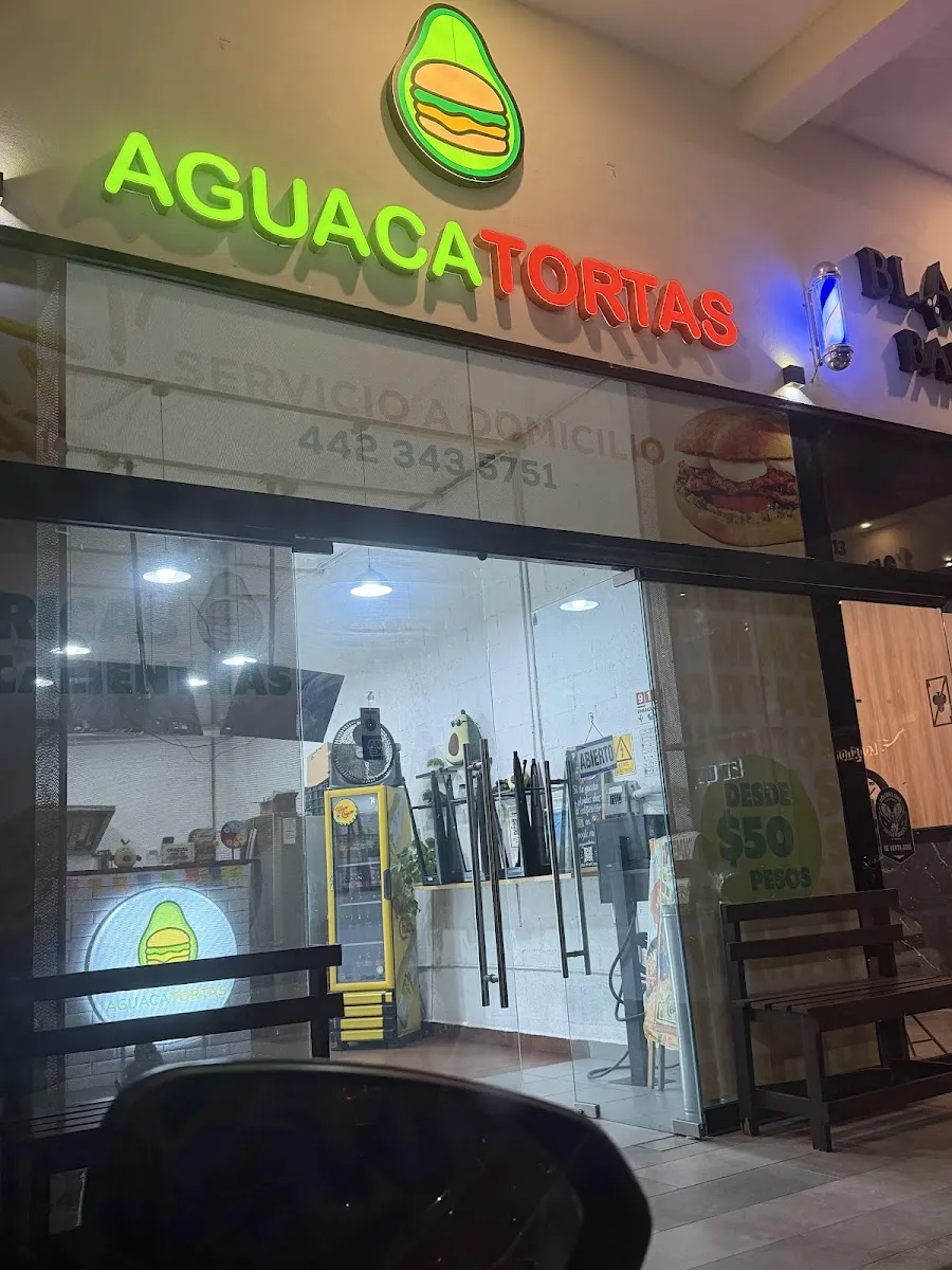 Fachada de Aguacatortas con su letrero verde de noche