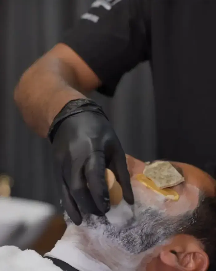 Barbero con guantes negros durante el ritual de barba