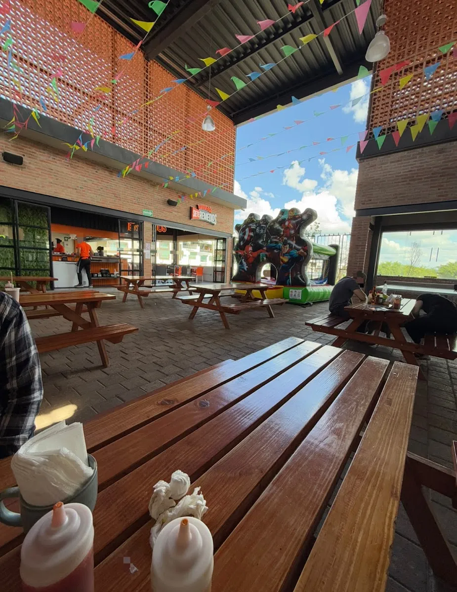 El patio de Barnaby con mesas de madera y papel picado