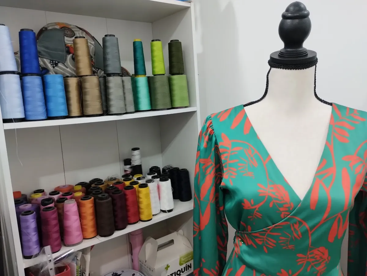 Hilos de colores y un vestido verde en un maniquí