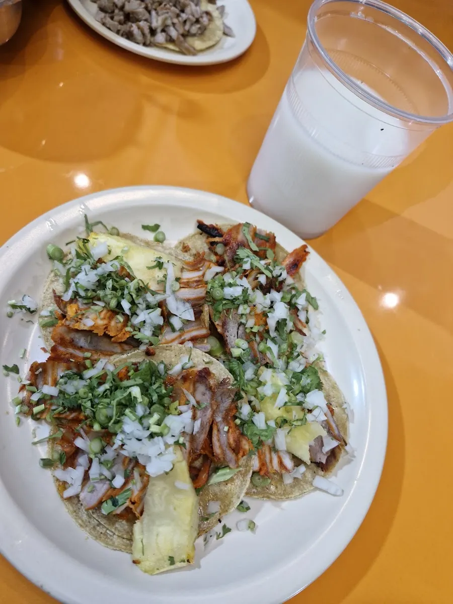 Tacos al pastor con cebolla y cilantro y un vaso de horchata