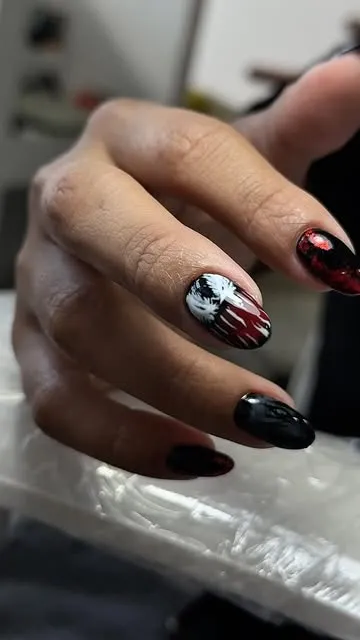 Uñas negras y rojas con un diseño de Venom