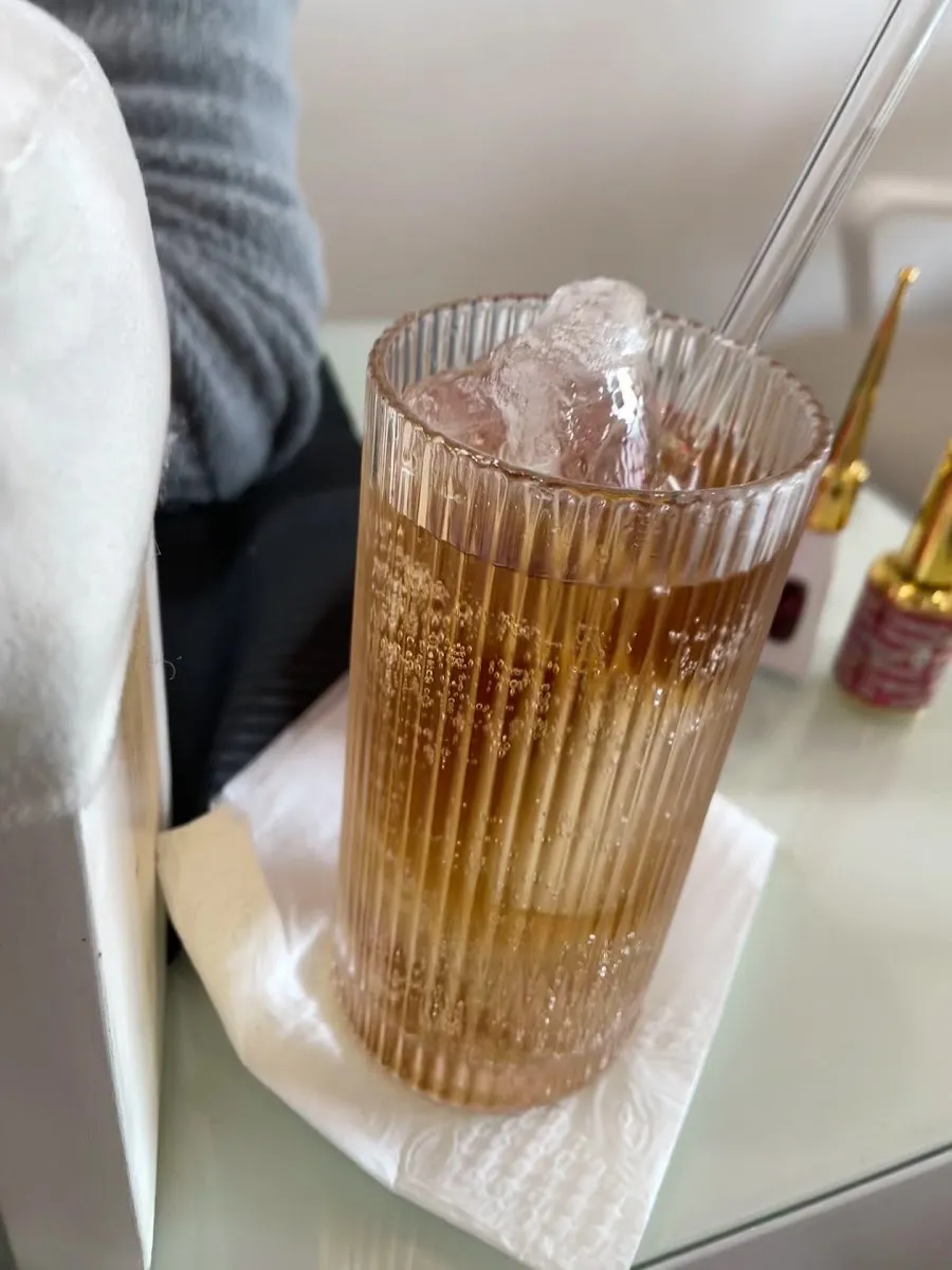 Bebida con hielo en un vaso de cristal junto a los esmaltes