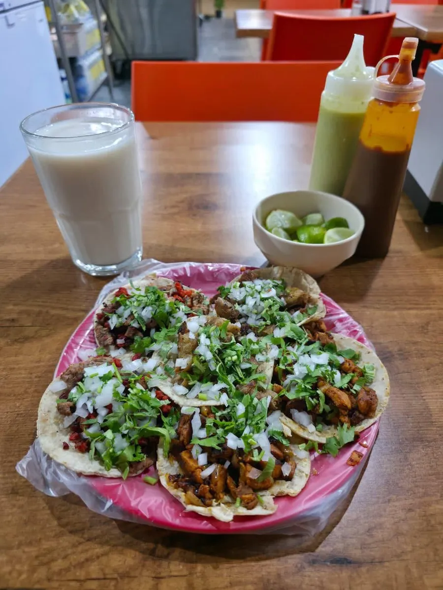 Tacos en un plato rosa con un agua de horchata