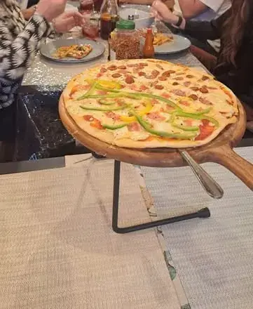 Pizza servida en una tabla de madera sobre la mesa