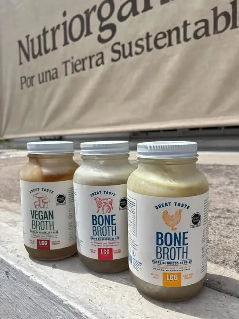 Frascos de caldo de hueso y caldo vegano frente al toldo de la tienda