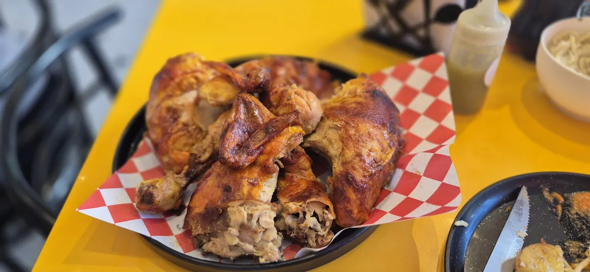 Pollo rostizado servido en un plato con papel a cuadros