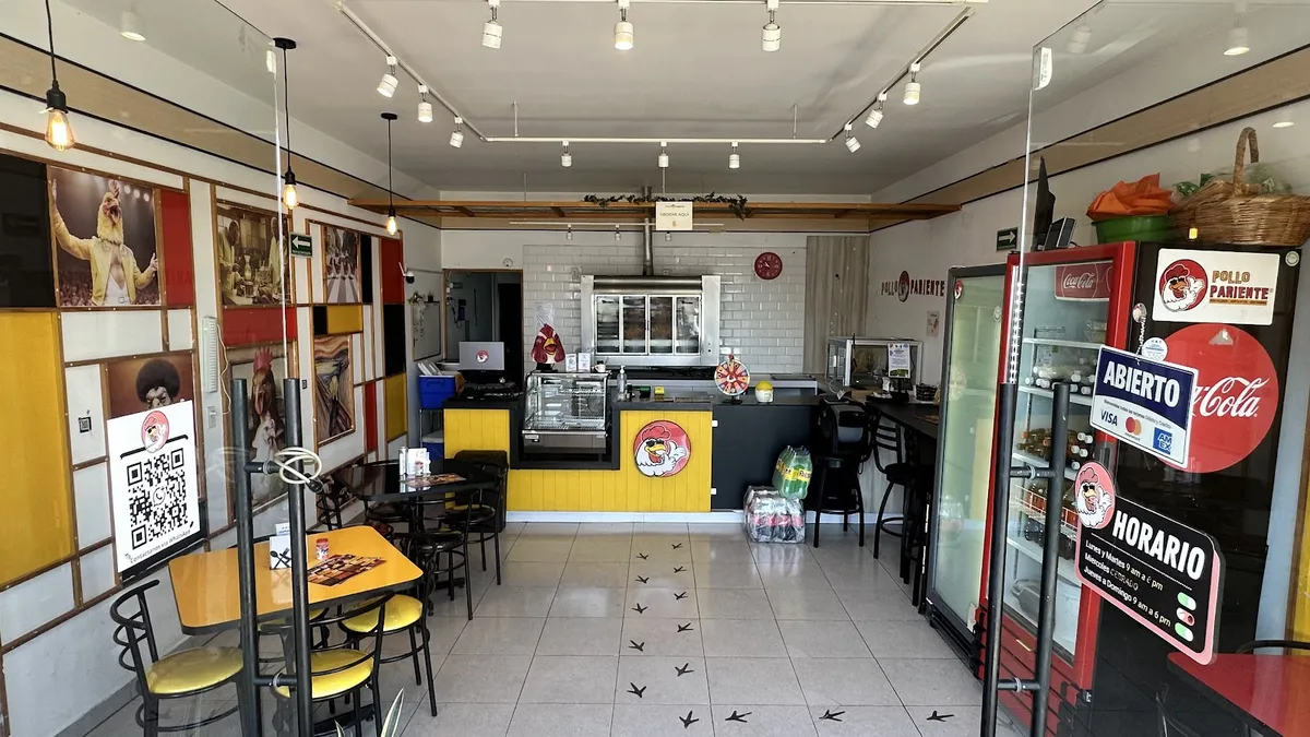 El comedor de Pollo Pariente con mesas amarillas y sillas rojas
