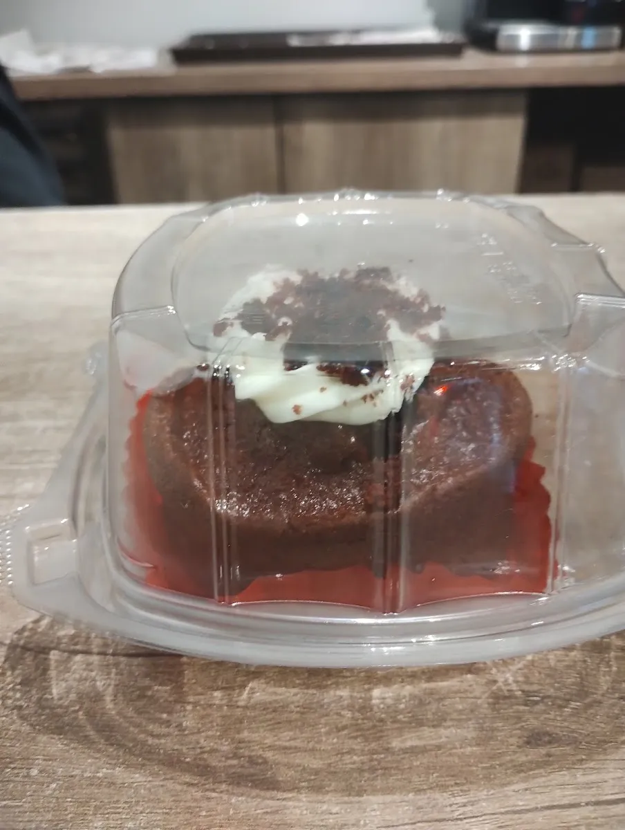 Pastel rojo con betún blanco en su caja transparente